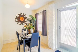 Enjoy meals in this stylish dining area with a table for two, a vase with a plant, and a bottle of wine.