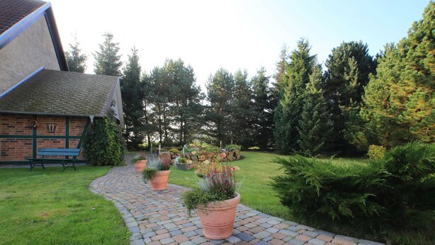 A brick pathway leading to a building with a green bench and potted plants. - Vacation apartment 3 - Rügen-Fewo 155 (Bergen auf Rügen)