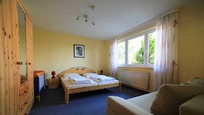 A bedroom with a wooden bed, a nightstand, a dresser, and a window with curtains. - Vacation apartment 3 - Rügen-Fewo 155 (Bergen auf Rügen)