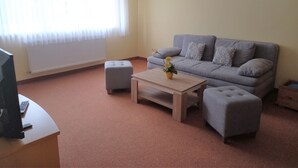 A living room with a grey sofa, two ottomans, a wooden coffee table, and a TV on a stand. - Vacation apartment 3 - Rügen-Fewo 155 (Bergen auf Rügen)