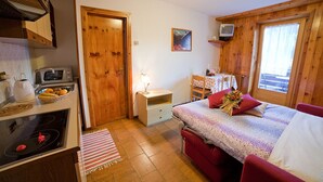 Een knus slaapkamer met een bed, nachtkastje en een kleine televisie.