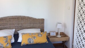 A bedroom with a bed, pillows, a bedside table with a lamp, and a wall-mounted light fixture.