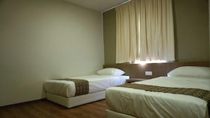 Una habitació d'hotel amb dos llits, un paviment de fusta i una finestra amb cortines.