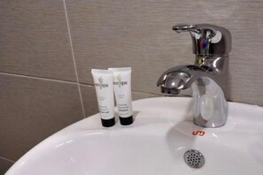 A bathroom sink with two tubes of lotion and a faucet. - Yew Hotel (Miri)