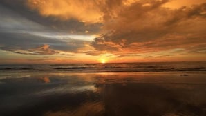 Un capvespre sobre una platja amb aigües tranquil·les que reflecteixen el cel.