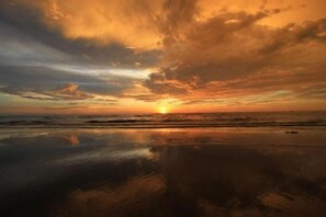 A sunset over a beach with calm waters reflecting the sky. - Yew Hotel (Miri)