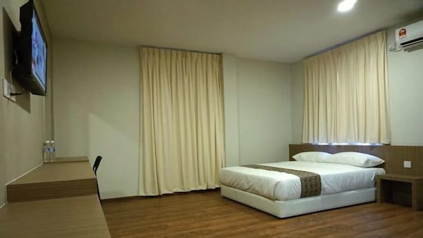 Habitació d'hotel amb un llit, una taula de treball i una televisió.