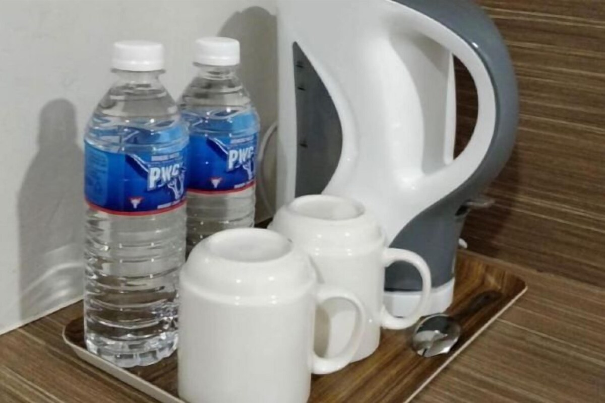 A tray with two water bottles and three white mugs on a wooden surface.