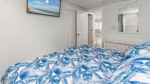 Een hotelkamer met een bed, een televisie waarop 'Central Reservations' staat, een raam en een deur naar een andere kamer.