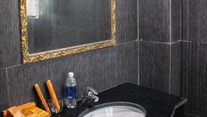 A bathroom with dark tiled walls, a black sink, a gold-framed mirror, and toiletries on the counter. - ZO Star Tam Dao (Tam Dao)