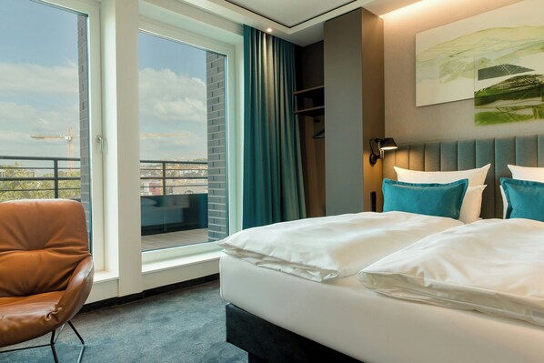 Une chambre d’hôtel avec un grand lit, une chaise, une vue sur la ville et un balcon.