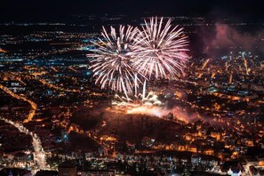 Ein nächtliches Stadtbild mit Feuerwerk über einem dicht besiedelten Gebiet.
