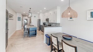 Une cuisine moderne avec des meubles blancs, un îlot central et des luminaires suspendus.