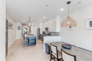 Una cocina moderna con armarios blancos, una isla central e iluminación colgante.
