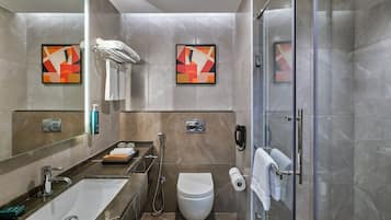 Un baño moderno con ducha de vidrio, lavamanos y retrete.