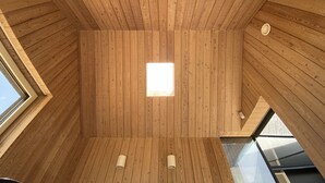 Interior de madera con tragaluz y dos lámparas fijadas a la pared.