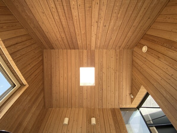 A wooden interior with a skylight and two wall-mounted light fixtures.