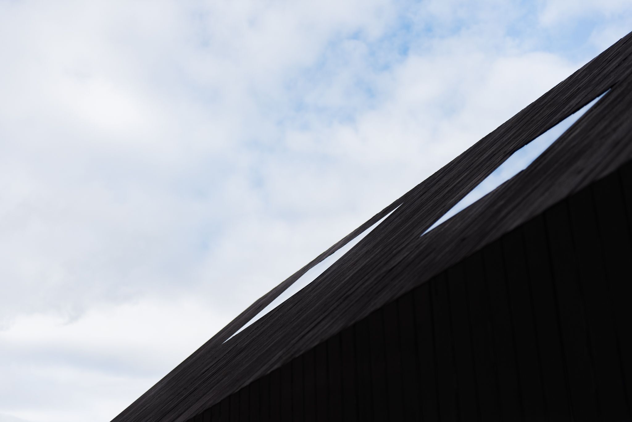 Un bâtiment doté d’un toit en pente, avec un ciel dégagé en arrière-plan.