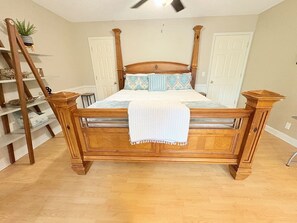 A wooden bed with a headboard, a ladder, and a shelf with plants and decorative items.