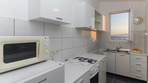 A modern kitchen with white cabinets, a microwave, a gas stove, and a sink.
