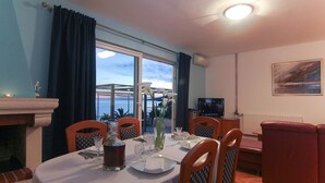 A dining area with a table set for two, a fireplace, and a view of the sea.