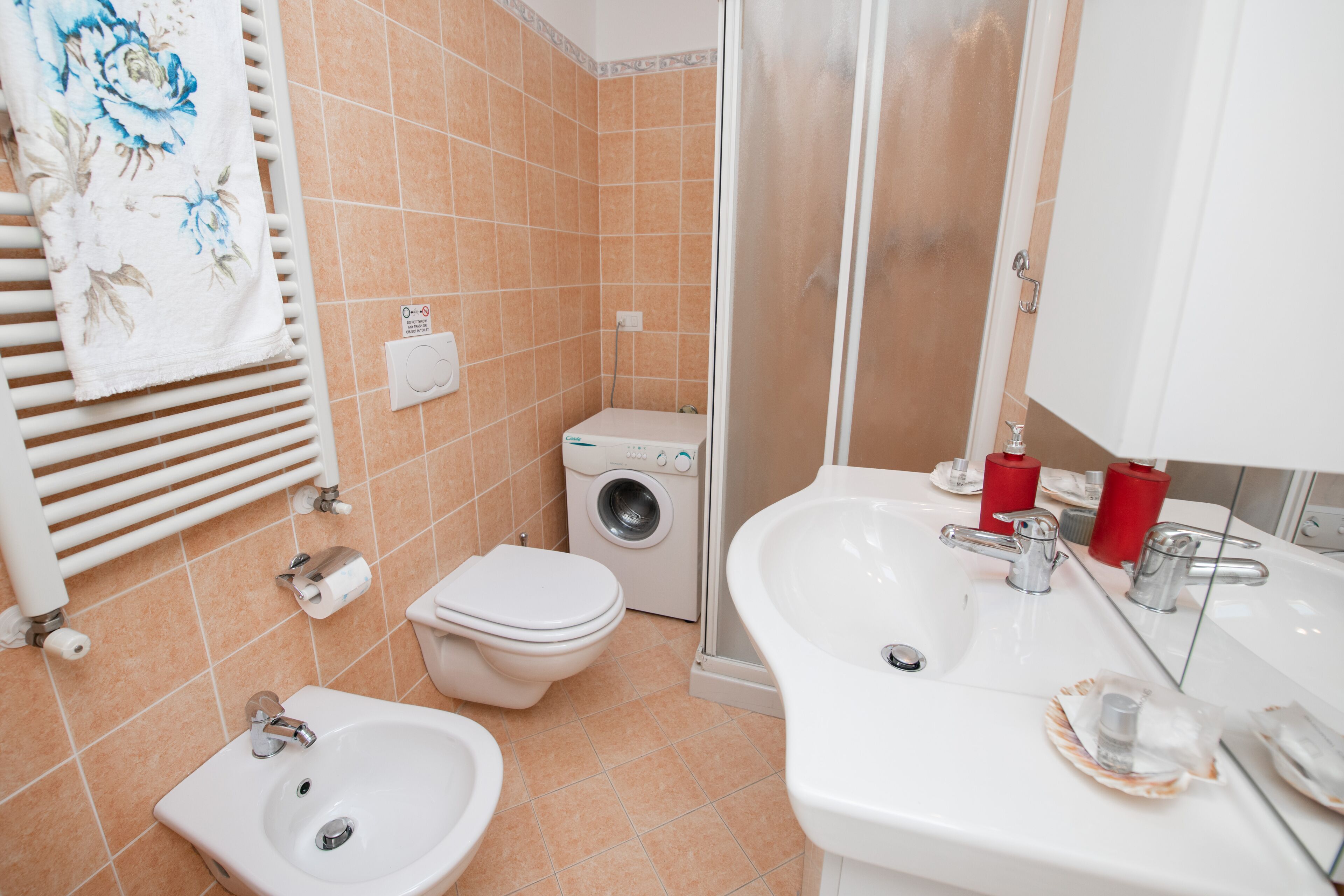 A bathroom with a sink, toilet, and washing machine.
