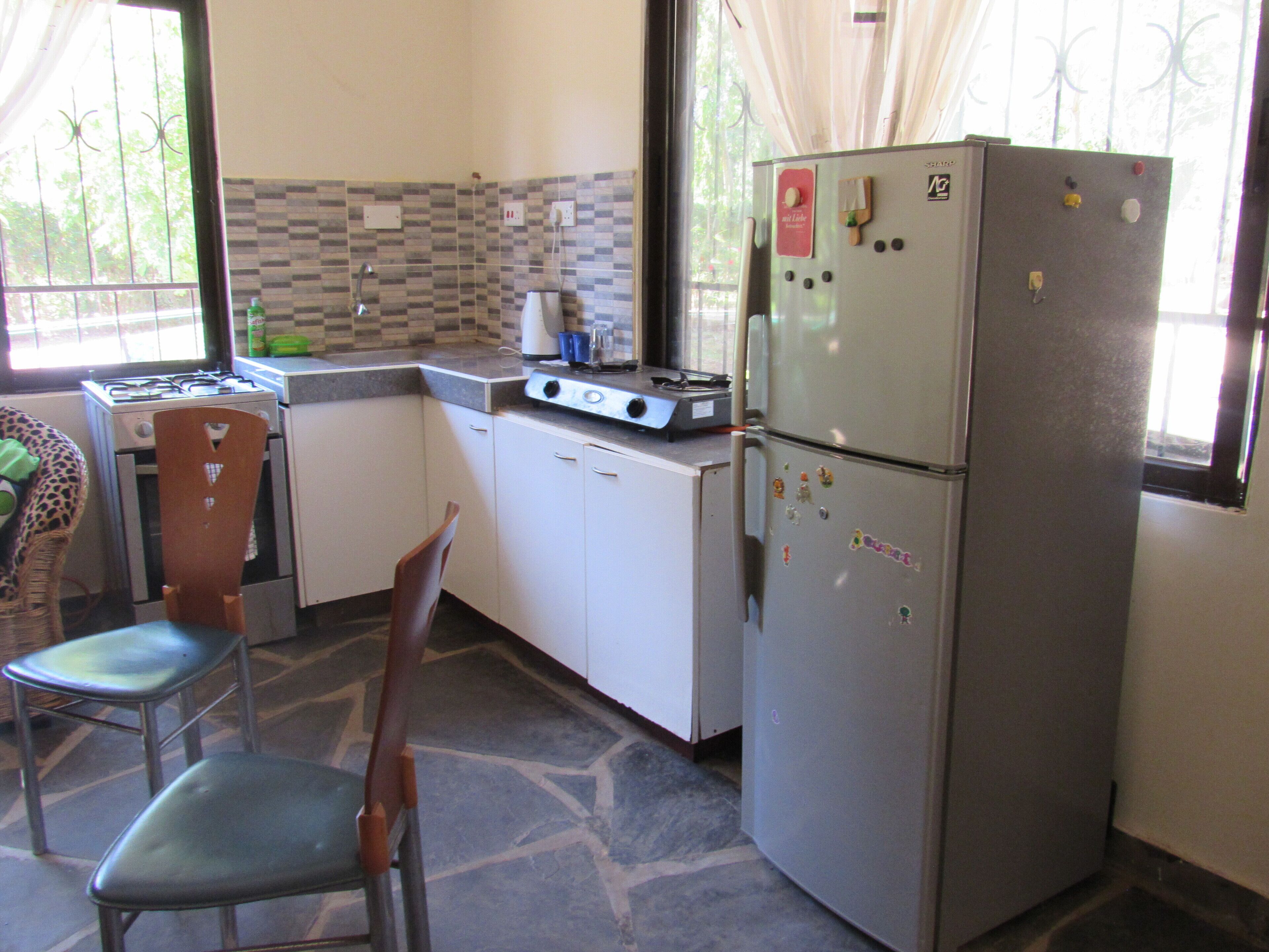 Een koelkast, een oven, een waterkoker, kookgerei, borden en bestek