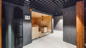 A modern interior with a glass partition, wooden benches, and a metal door. - Apartamenty Sun & Snow Riverside Sienna (Gdansk)
