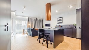 A modern kitchen with a central island, bar stools, and a pendant light. - Apartamenty Sun & Snow Riverside Sienna (Gdansk)