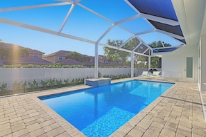 A swimming pool with a clear blue water, surrounded by a covered patio area with a white roof structure.