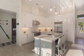 A modern kitchen with white cabinetry, a central island, stainless steel appliances, and pendant lighting. - Beachy Home | Pool and Steps to Beach/Food/Shops (Marco Island)