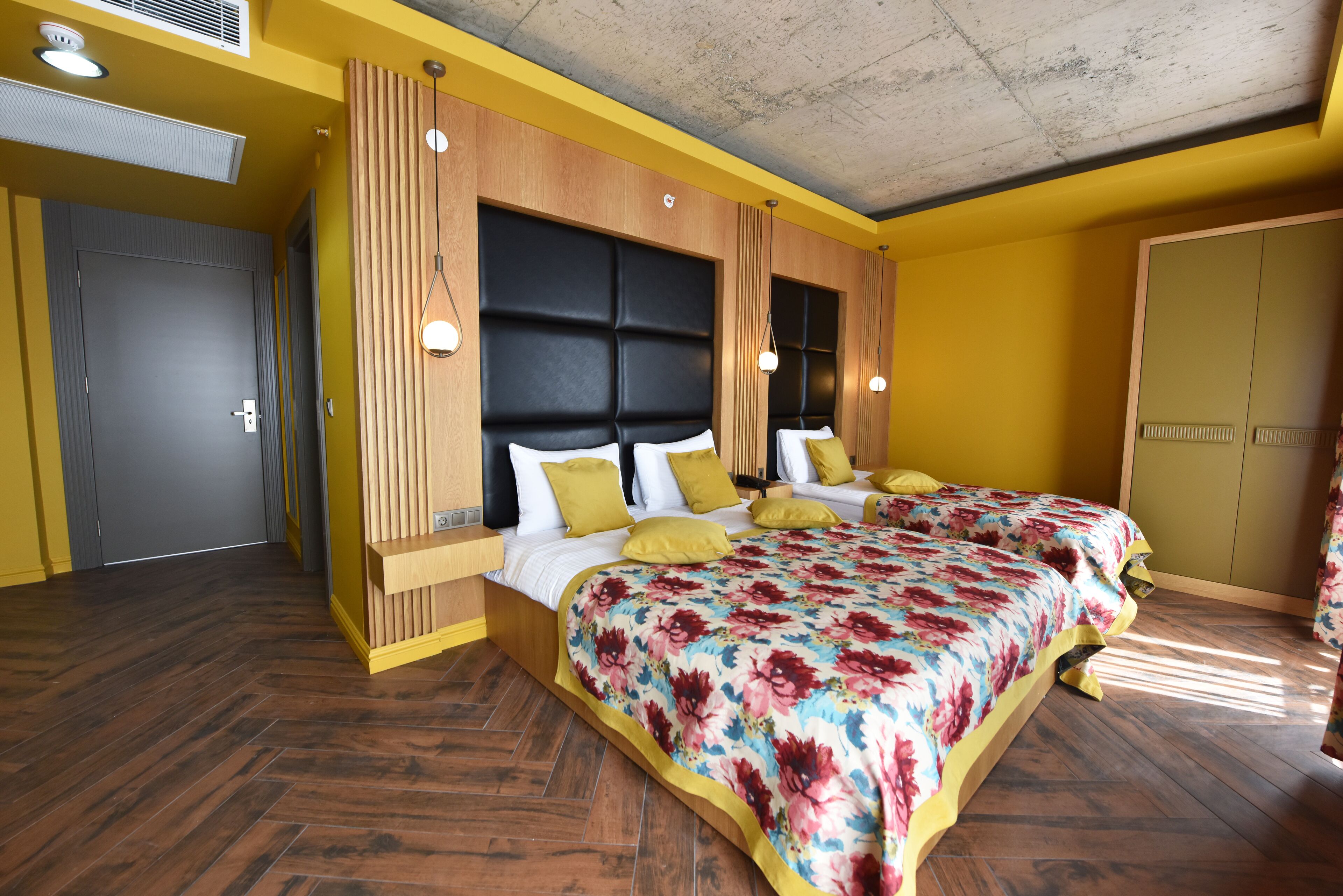 Un dormitorio con una cama grande, cabecero de madera y una pared de acento amarilla.