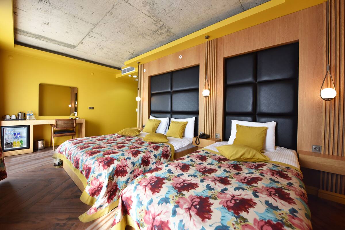 Habitación de hotel con dos camas, un escritorio y una pequeña cocina.