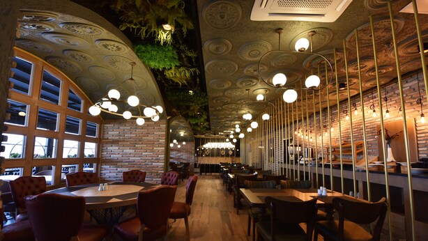 A restaurant with a brick wall, wooden tables, and chairs. - Bayberd Hotel (Bayburt)