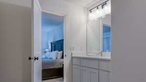 Une salle de bain moderne avec des meubles blancs, un grand miroir et un meuble-lavabo doté d’un porte-serviettes.