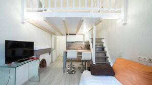 Une chambre d’hôtel de taille réduite, comprenant un lit, une télévision, une kitchenette et un petit coin repas.