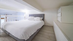 Une chambre à coucher avec un lit, une armoire blanche et une vue sur l’extérieur.