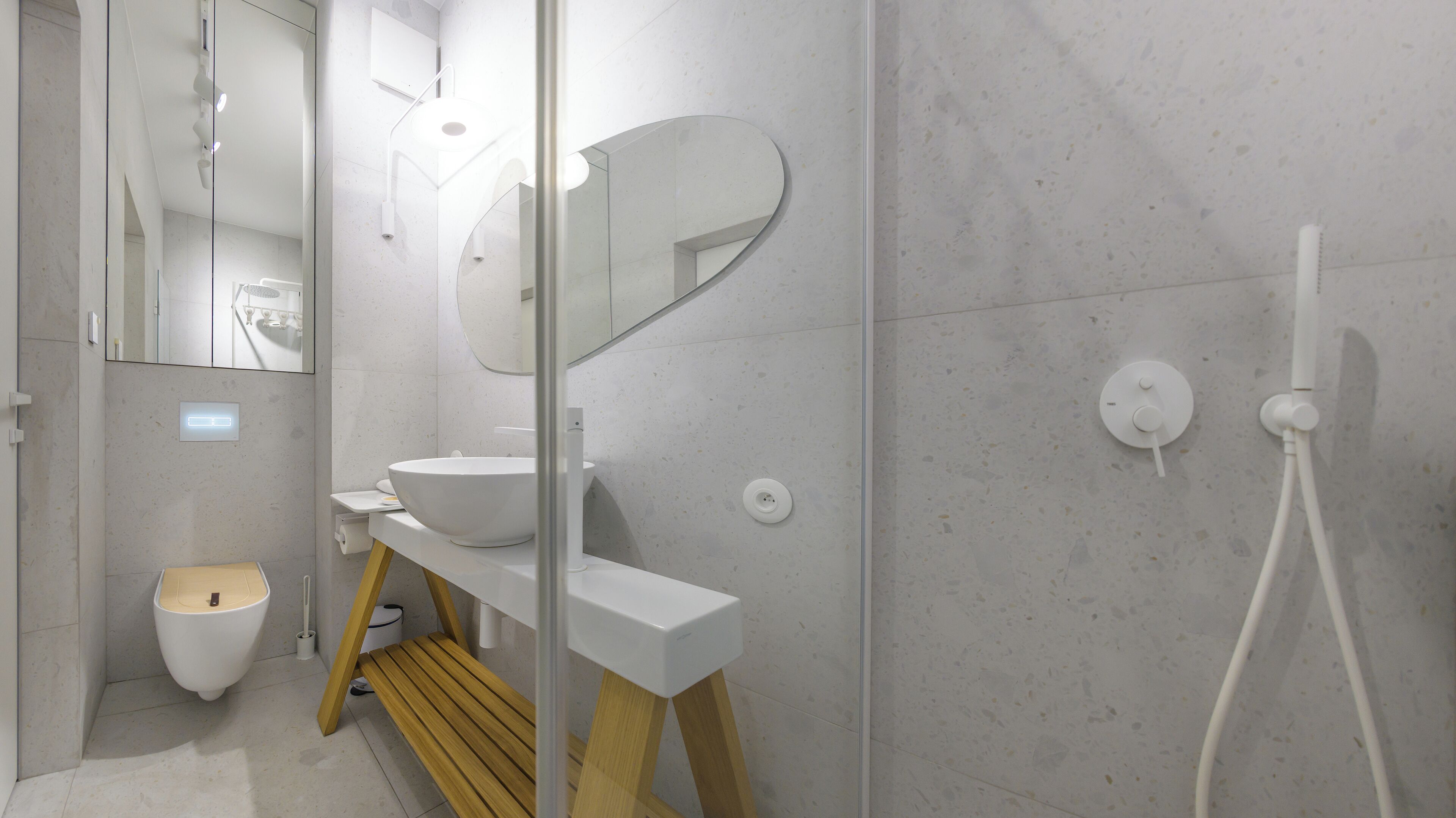 Een moderne badkamer met een wit wastafel, een spiegel, een douche en een toilet.