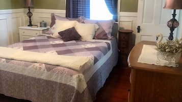 A bedroom with a bed, nightstands, a dresser, a lamp, a swan decoration, and a wreath on the wall.