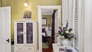 A narrow hallway with a white cabinet, a small table with a vase of flowers, and a door leading to a bedroom. - Private 3 room Queen Suite w/Kitchenette  (Port Deposit)