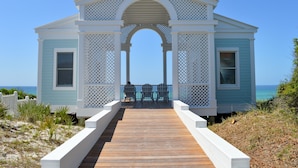 Une maison de plage dotée d’une terrasse en bois et de deux chaises donnant sur l’océan.