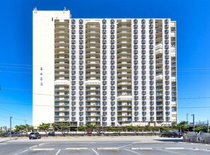 Un grand hôtel à plusieurs étages, doté d’une façade uniforme, de nombreux balcons et surplombant un ciel dégagé.