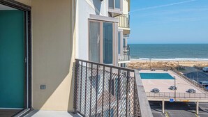 A balcony with a view of the ocean, a parking area, and a pool. - 2 Bedroom Condo With Ocean View and Outdoor Pool! (Ocean City)