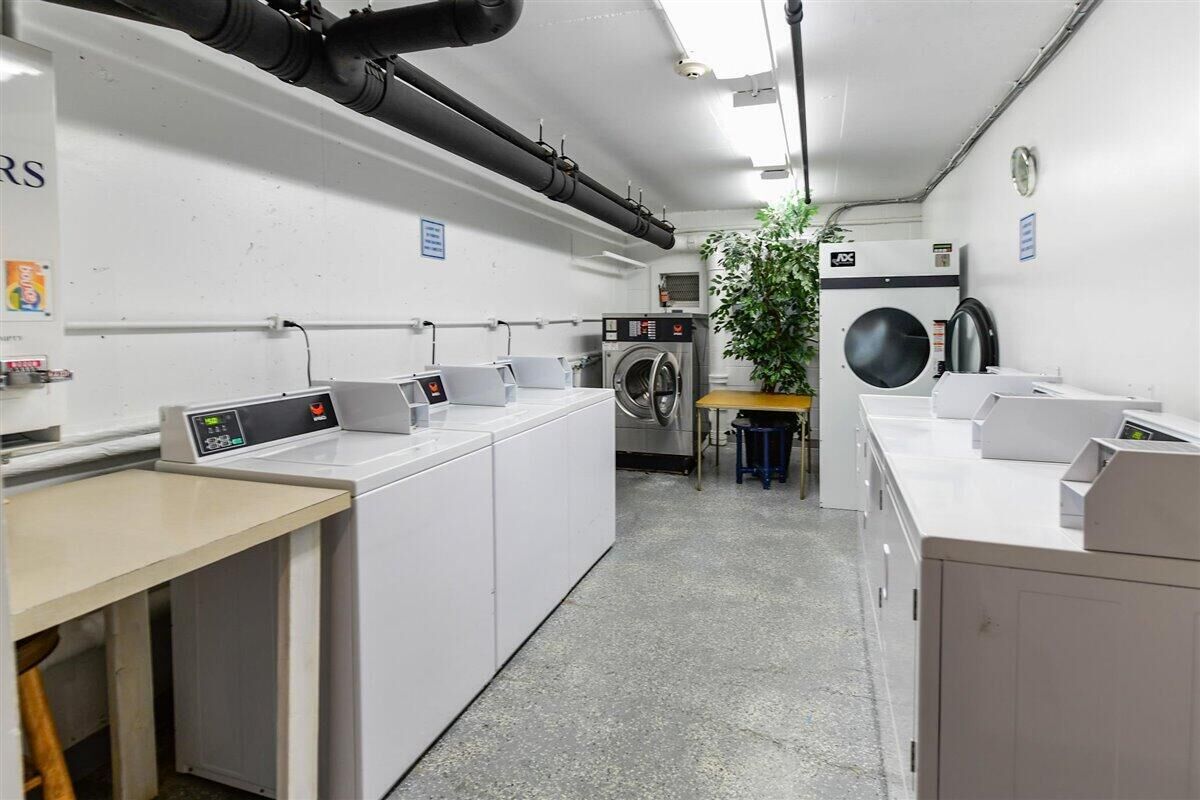 Una sala amb diverses rentadores, una màquina d'assecar i un panell de control.