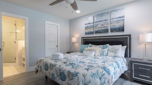 A bedroom with a bed, a nightstand, a ceiling fan, and artwork on the wall. - 44 Forest Gardens: Luxurious Remodeled Villa, Walk to Beach, Pool, Free Bikes (Hilton Head Island)