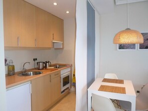 Une cuisine compacte dotée de meubles en bois, d’un four à micro-ondes, d’un évier et d’un coin repas avec une table et des chaises.