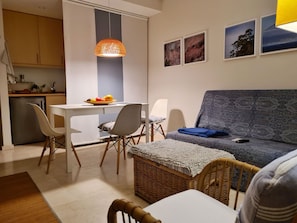 Un salon moderne comprenant un canapé, une table à manger, des chaises et un coin cuisine.