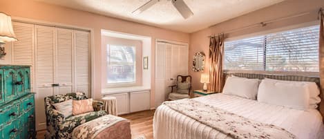 A bedroom with a large bed, a ceiling fan, a dresser, and a chair.