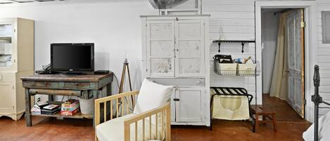Una habitación rústica con una mesa de madera, una silla blanca, un televisor y un armario.