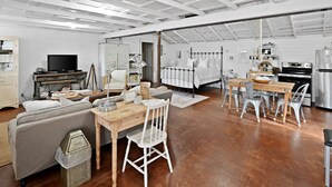 A spacious living area with a sofa, dining table, and chairs, a television, and a kitchen area with appliances.